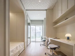A modern minimalist office and bedroom with white furnishings and patterned ceiling.