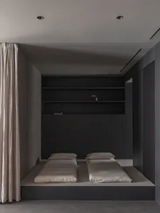 A minimalist bedroom with black wooden furniture and beige bedding.