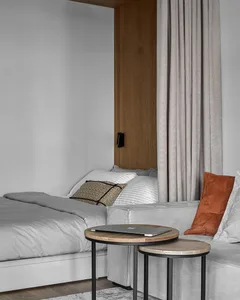 A minimalist bedroom featuring a grey bed with white and brown pillows, and a coffee table.