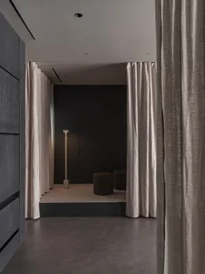 A minimalist living space with neutral-toned textiles and a sleek, modern floor lamp.