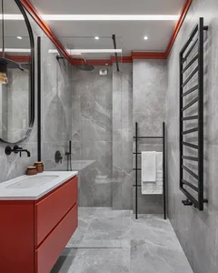 Modern bathroom with marble walls, red accents, and a glass shower enclosure