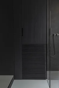 A modern bathroom with black wood elements and a minimalist aesthetic.