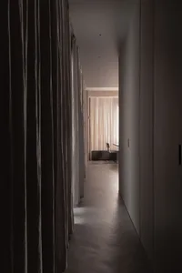A modern corridor with fabric curtains leading to a well-lit area.