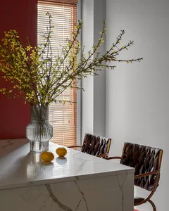 Modern kitchen with a marble countertop, a vase of yellow flowers, and two lemons.