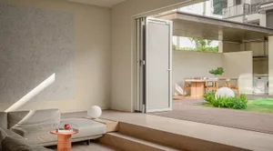 A modern living room with wooden floors, glass bi-folding doors to an outdoor area, a white sofa, and a small table with an a