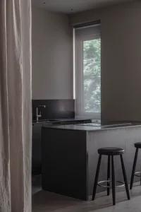 Modern minimalist kitchen with black cabinets, stainless steel appliances, and a black countertop.