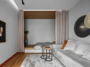 A minimalist living room with grey furnishings, a wooden side table, and a comfortable sofa.