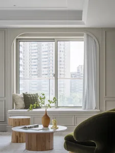 A minimalist living room with clean lines, a large window showcasing urban architecture, and neutral-toned furnishings.