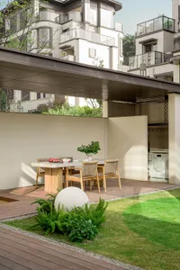 Modern patio with wooden flooring, green grass, and decorative plants.