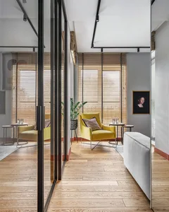 A modern living room featuring a yellow upholstered chair with a cushion, placed on a wooden floor and complemented by wooden
