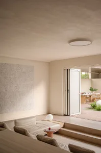 A modern living room featuring a wooden flooring, a white leather sofa, and a minimalist design with natural light.