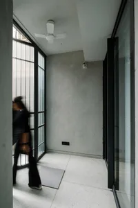 Minimalist apartment entrance featuring concrete and glass materials.