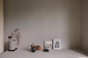 A minimalist shelf with ceramic vases, books, and a potted plant.