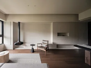 A minimalist modern living room featuring a suspended fireplace, a single leather armchair, and a sleek, modern coffee table.