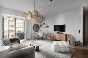 A minimalist living room featuring a grey sofa, marble coffee table, and concrete floors.