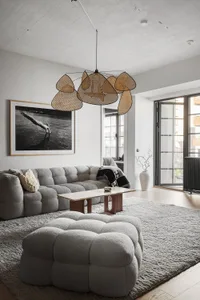 Modern living room featuring a textured grey sofa, minimalistic decor, and a unique hanging light fixture.