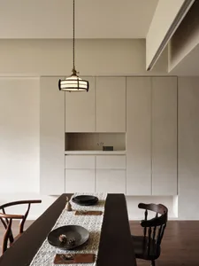 Modern dining room featuring sleek white cabinets with walnut wooden table and minimalist decor.