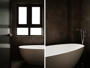 Minimalist bathroom with dark tiled walls and a freestanding tub.