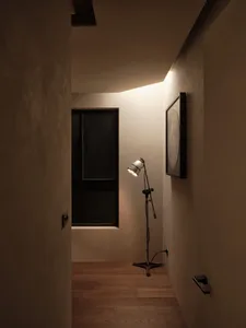 A minimalist interior design featuring metallic floor lamp, wooden floors, and smooth plaster walls.