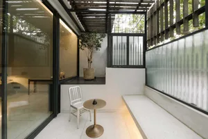 Modern balcony with concrete floor, glass walls, and potted plant.
