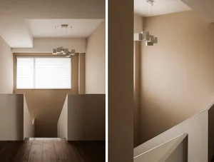 A minimalist, interior design space featuring neutral tones with a geometric lighting fixture and a window with light-colored