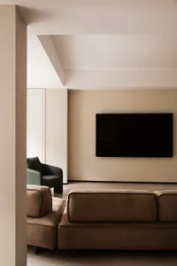 A modern minimalist living room with a brown leather sectional sofa and a green accent chair.