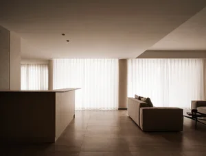 A minimalist living room with neutral-colored fabrics and a large window.
