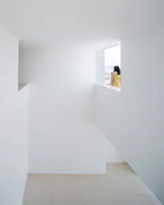 A minimalist white room with a window showcasing sculpture.