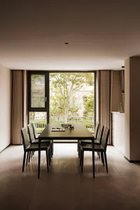 Modern dining room with black leather chairs and black rectangular dining table, large glass window with trees outside, brown