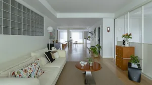 A modern living room with wooden furniture, a white sofa, and a round wooden coffee table.