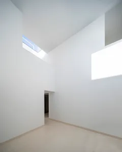 Modern white minimalist interior with high ceilings and natural light.