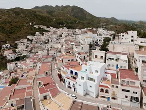 Aerial view of a white stone and earth cityscape with a mountainous backdrop