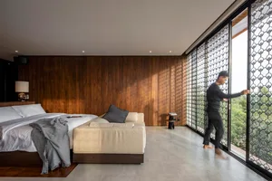 A modern bedroom featuring a comfortable bed and couch with white bedding and wood paneling.