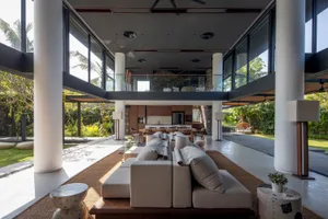 A modern living room with concrete finishes, large windows, and a spacious layout.