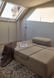 A modern minimalist living room with a fabric sectional sofa, a patterned rug, and a floor lamp.