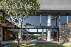 A modern residential interior featuring concrete, glass, and stone materials.