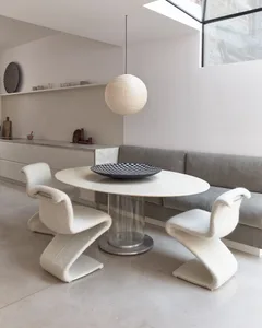 A minimalist kitchen with concrete finishes, featuring a round table with a black and white checkerboard tray on top, three w