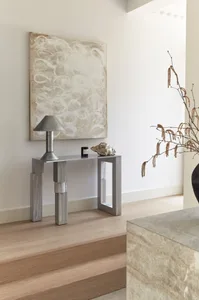 Modern, minimalist, concrete console table with a lamp, vase, and abstract painting on the wall.