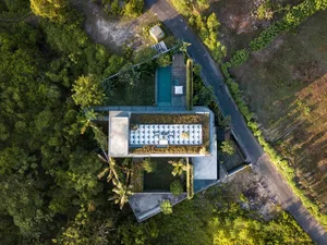Aerial view of a modern house with a concrete exterior and lush greenery.