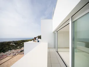 A modern residential building with a concrete exterior overlooking a scenic landscape.