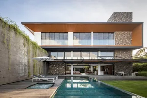 A modern residential exterior featuring stone, concrete, and wooden textures.
