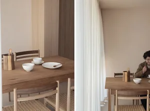 A modern, minimalist dining room with wooden furniture and white tableware.