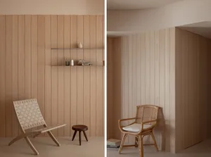 A minimalist interior design featuring wooden paneling, a woven chair, and a small stool with decorative items on a shelf.