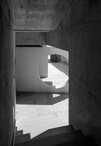 A modern architectural space featuring a concrete interior with lighting and circular archways.