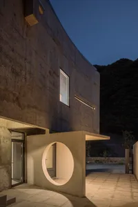 Concrete building exterior with circular entrance at night.