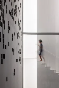 A blurred figure walking on a glass stairway with a modern architectural design.