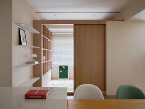 A modern home office featuring wooden shelves and a sliding door.