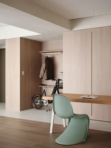 A modern home office featuring a wooden desk, a green chair, and a white wall.