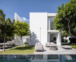 Modern house with a white concrete exterior and large glass windows.