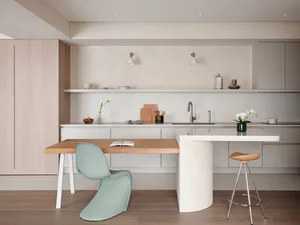 Contemporary kitchen featuring concrete countertops, wooden table, and metallic accents.